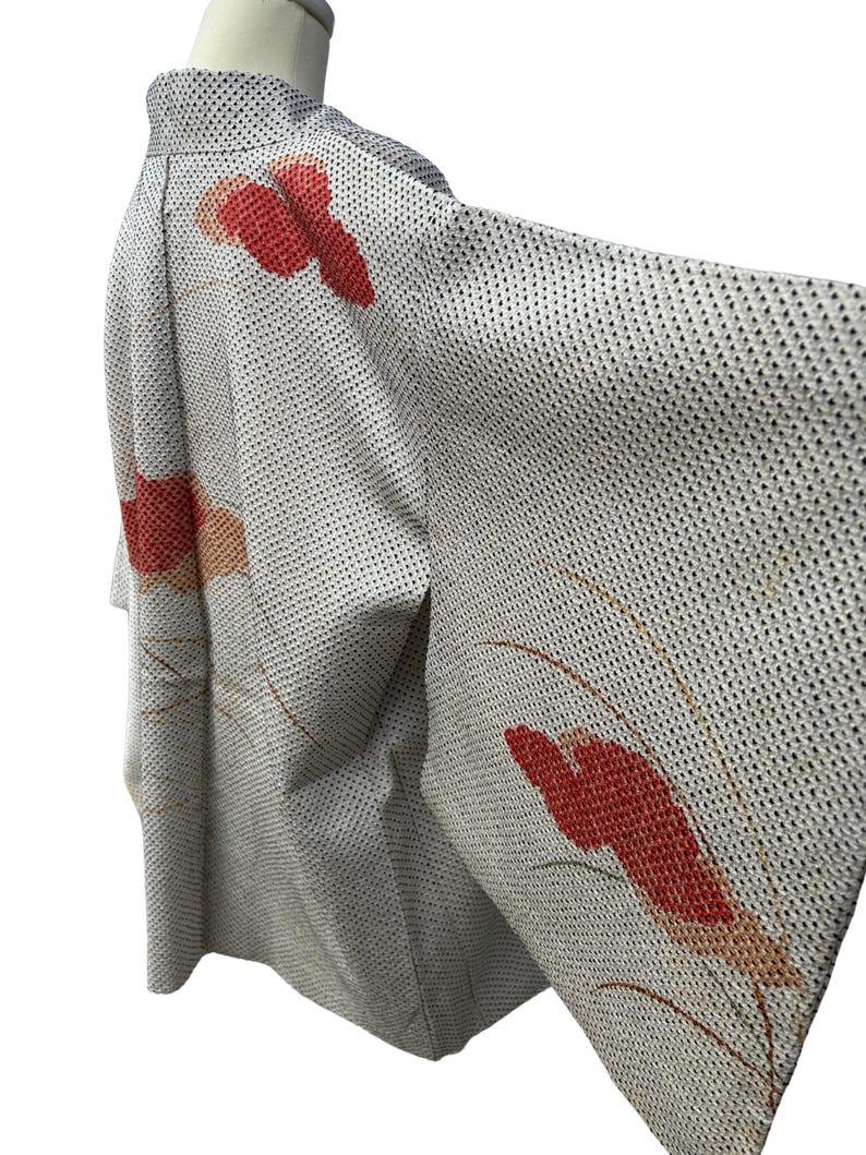 May include: A white Japanese kimono with a red and orange floral pattern. The kimono is made of a lightweight fabric and has a traditional design.