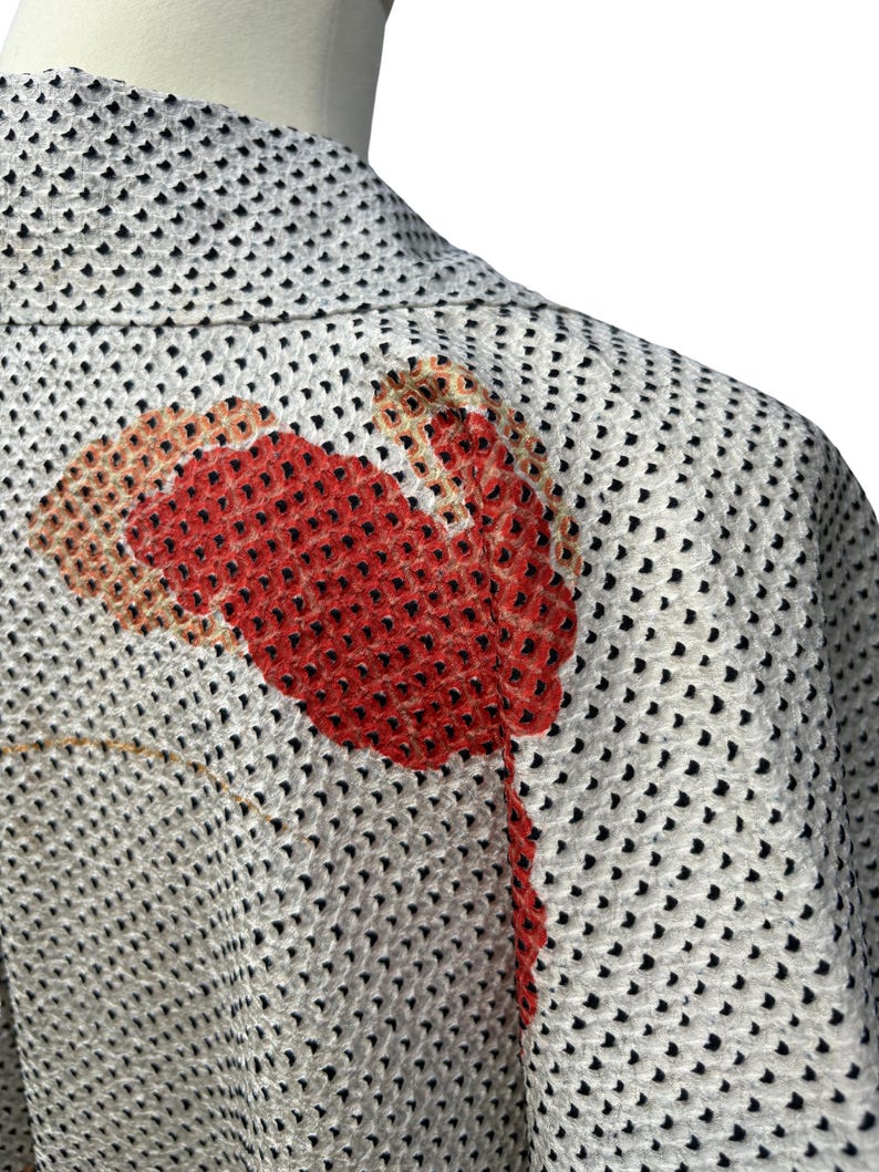 May include: A white kimono with a black polka dot pattern and a red and orange floral design on the back.