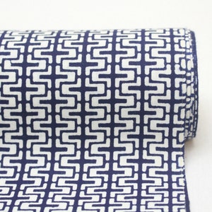 May include: A roll of white fabric with a navy blue geometric pattern. The pattern is made up of repeating squares with a zig-zag design.