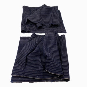 May include: Several pieces of navy blue fabric with a subtle striped pattern. The fabric is rolled and folded, showcasing its texture and potential for various sewing projects. The fabric appears to be a medium weight.