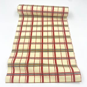 May include: A roll of cream-colored fabric with a red, brown, and blue plaid pattern.