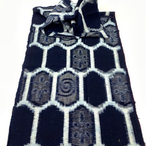 May include: A blue and white fabric with a geometric pattern. The fabric has a fringed edge and is folded in half.