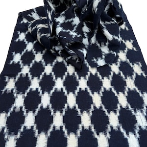 May include: A folded textile with a repeating pattern of navy blue and white diamond shapes. The fabric is draped, revealing the pattern and texture. The design is a classic, geometric style.
