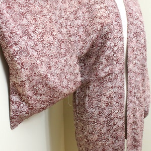 May include: A long-sleeved, burgundy kimono with a white floral pattern. The kimono is made of a silky fabric and has a traditional Japanese design.