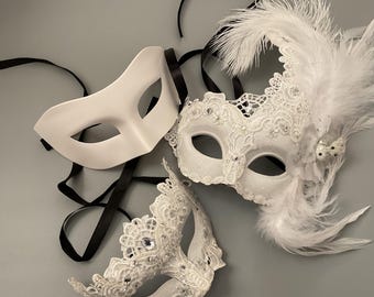 May include: Three white masquerade masks with black ribbons. One is plain, the others feature lace, rhinestones, and feathers. These masks are designed for a formal event or costume party.