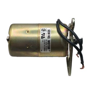 May include: A cylindrical gold-toned sewing motor with a metal mounting bracket on one end. A white label displays the text SEWING MOTOR, YDK MODEL YM-230A-1C, 110/125V AC 50/60Hz, 0.5A, and safety certification logos. Two black wires extend from the side.