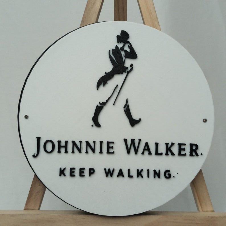 May include: A round, white sign with a black border and the Johnnie Walker logo. The logo features a walking figure with a cane. The text "JOHNNIE WALKER. KEEP WALKING." is printed in black below the logo.