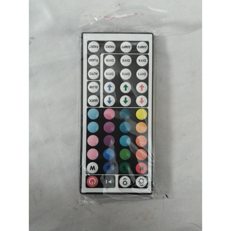 May include: A rectangular black remote control with numerous buttons and a variety of colors. The buttons include options for color selection, brightness, and special effects like flash and fade. The remote is packaged in a clear plastic bag.