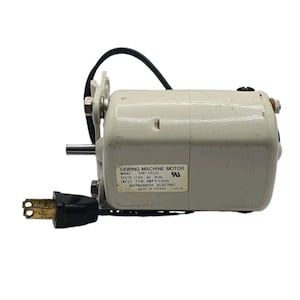 Puede incluir: Un motor de máquina de coser color blanco hueso con cable de alimentación y enchufe negros. La etiqueta dice: SEWING MACHINE MOTOR, MODEL 3M-752H, VOLTS 115V AC 60Hz, INPUT 70W AMP'S 0.69A, MATSUSHITA ELECTRIC, MADE IN TAIWAN. Incluye soporte metálico.