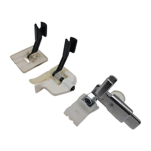 May include: Three sewing machine presser feet. One features a clear plastic base with a black shank. Another has a white plastic base with a black shank. The third is a metallic silver presser foot with a white plastic component and a screw.