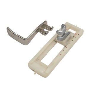 Op de afbeelding: Een zilverkleurige metalen naaivoet voor een naaimachine met een gebogen arm en een rechthoekig wit plastic knoopsgatvoetje met een centrale opening en rode meetmarkeringen aan de zijkant voor nauwkeurige uitlijning.