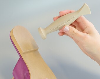 May include: A beige tool with the text "ICANMAKE SHOES" on it is being used to smooth the sole of a purple shoe.