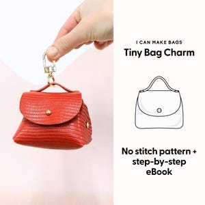 Op de afbeelding: Een kleine, rode tashanger met een getextureerd oppervlak, gouden hardware en een handvat aan de bovenkant. De tekst "I CAN MAKE BAGS Tiny Bag Charm" wordt weergegeven. De afbeelding bevat ook een lijntekening van een tas en de tekst "No stitch pattern + step-by-step eBook."