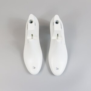 May include: A pair of white shoe trees with a metal spring mechanism. The shoe trees are labeled "41" and have a round toe shape.