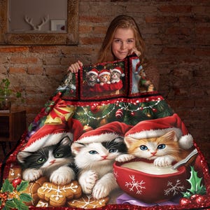 May include: A Christmas-themed blanket featuring three kittens wearing Santa hats, with a red bowl of milk and gingerbread cookies. The blanket has a festive design with Christmas tree elements and a red border.
