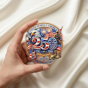 May include: A clear, circular commemorative emblem with the text "UNITED STATES OF AMERICA" and "250 ANNIVERSARY 1776-2026." The design features an eagle, American flags, a soldier, a guitar, and military boots.