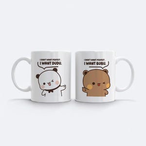 May include: Two white ceramic mugs with a cartoon bear design. One mug features a panda bear, the other a brown bear. Each mug has the text "I DON'T WANT PERFECT... I WANT DUDU" and "I DON'T WANT PERFECT... I WANT BUBU."