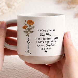May include: A white ceramic mug with a black handle and the text "But first, coffee" in a handwritten style. The mug is on a white surface.