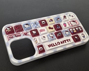 May include: A white and blue phone case with a keyboard design featuring Hello Kitty characters. The case has a grid of square buttons in red, white, and blue, with various Hello Kitty designs. The words "HELLO KITTY" are printed on the case.