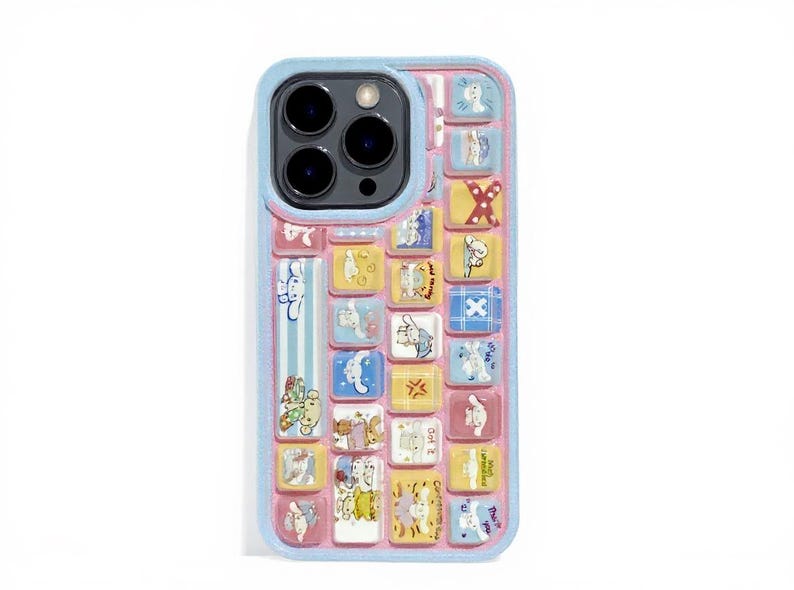 May include: A phone case with a keyboard design featuring colorful cartoon characters. The case has a light blue border and a pink background. The keyboard keys are yellow, blue, and pink, with various illustrations.