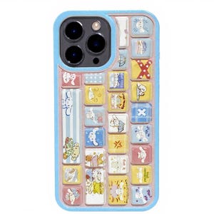 May include: A blue phone case with a keyboard-like design featuring cartoon characters. The case has a light blue border and a pink interior. The keyboard keys are yellow, blue, and white, with various cartoon illustrations.