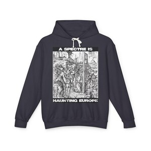 May include: Navy blue hoodie with a white graphic. The graphic features a detailed black and white illustration of a historical scene, with the text "A SPECTRE IS HAUNTING EUROPE" in a bold, white font. The hoodie has a drawstring hood.