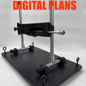 Könnte beinhalten: Eine schwarze, rechteckige Plattform mit Metallrahmen und verstellbaren Komponenten. Der Rahmen hat zwei vertikale, chromfarbene Stangen und eine horizontale schwarze Stange. Der Text "DIGITAL PLANS" ist orangefarben.