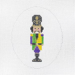 May include: A purple, green, and gold nutcracker with a black hat and a white face. The nutcracker is standing on a white background.