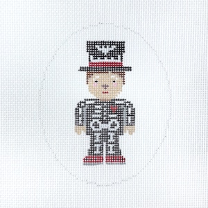 May include: A cross-stitch embroidery on white fabric featuring a figure wearing a black top hat with a red band and a white bat emblem, and a black skeleton costume with white bone details, a small red heart, and red shoes, enclosed in a stitched oval.