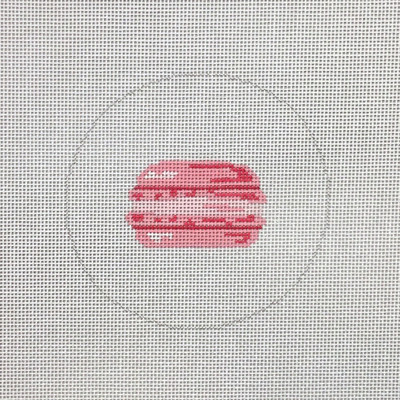 Puede incluir: Una galleta macaron rosa y blanca sobre un fondo blanco.