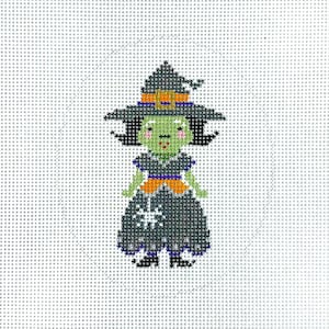 May include: A cross-stitch design of a green-skinned witch wearing a black hat with an orange buckle and a black dress with a white snowflake. The witch has black hair and is smiling. The background is a light gray grid.