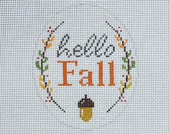 May include: A needlepoint canvas with a wreath of leaves and berries surrounding the text "Hello Fall" in orange and gray lettering. An acorn is below the text.