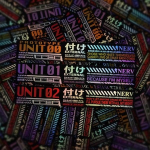May include: A collection of rectangular stickers with Japanese text and English phrases. The stickers feature the words "UNIT 00", "UNIT 01", and "UNIT 02" in bold, along with other text and graphics in various colors.