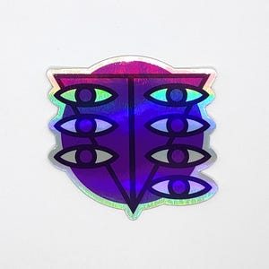 Könnte beinhalten: Holografischer Aufkleber mit einem symmetrischen Design aus sechs stilisierten Augen, die in zwei vertikalen Spalten angeordnet sind. Die Augen sind schwarz umrandet, mit weißen Iris und grünen und blauen Farbverläufen. Der Aufkleber hat ein violett-silbernes schillerndes Finish.