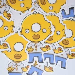 Peut inclure: Collection d'autocollants découpés représentant un personnage de dessin animé à la peau jaune, une chemise blanche, un pantalon bleu et une tête en forme de donut. Le personnage tient un donut. Les autocollants sont sur fond blanc.