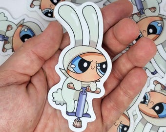 May include: A white sticker featuring a cartoon character in a bunny costume riding a pogo stick. The character has large blue eyes and an angry expression. Other stickers are visible in the background.