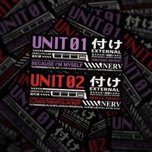 May include: A collection of black and purple stickers featuring Japanese text and the words "UNIT 01" and "UNIT 02" in bold, with additional text including "EXTERNAL" and "NERV". The stickers have a futuristic, anime-inspired design.