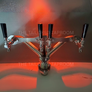 May include: A stainless steel draft beer tap system with five black tap handles. The system is mounted on a textured surface with the text "THE TAILORED TAPROOM". The image has a red and orange glow.