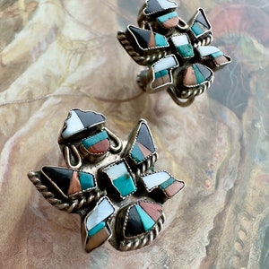 May include: A pair of silver earrings with a geometric design. The earrings are made of silver and feature a variety of colorful stones, including turquoise, coral, and mother-of-pearl.