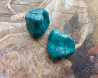 May include: Two teal blue ceramic heart-shaped beads with a crackled glaze finish.