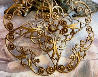 May include: A gold-toned metal hair comb with a delicate, intricate design featuring swirls and circles. The comb is made of a filigree pattern and has a vintage aesthetic.