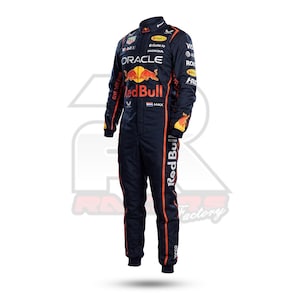 Puede incluir: Un traje de carreras azul marino oscuro con el logotipo de Oracle Red Bull Racing en el pecho, con ribetes naranjas en los costados y las mangas. El traje incluye varios logotipos de patrocinadores, el texto "MAX" con una bandera holandesa.