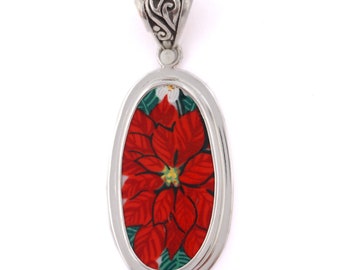 May include: Silver oval pendant with a red poinsettia flower design.