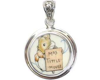May include: A silver pendant featuring a round porcelain cameo with a depiction of Mrs. Tittlemouse from Beatrix Potter's children's book, holding a sign that reads "MRS. TITTLE-MOUSE".
