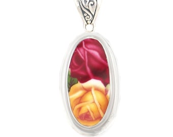 May include: A silver oval pendant with a red and yellow floral design. The pendant has a detailed silver bail.