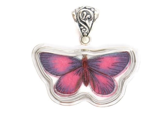 May include: A silver pendant featuring a pink and purple butterfly encased in glass. The pendant has a detailed silver bail.