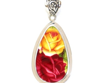 May include: A silver teardrop-shaped pendant with a red and yellow rose design.