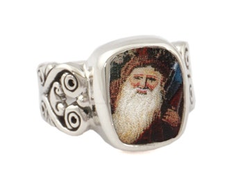 May include: A silver ring with a square-shaped setting featuring a colorful image of a bearded man with a crown. The ring band has a decorative design.