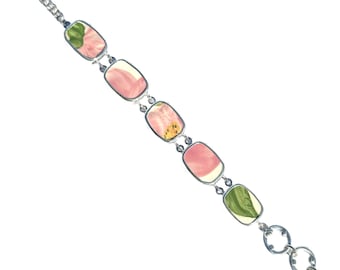 May include: A link bracelet featuring five rectangular ceramic tiles set in silver-toned metal frames. Each tile displays a unique floral pattern in shades of pink, green, and yellow. The bracelet includes a toggle clasp and circular links.