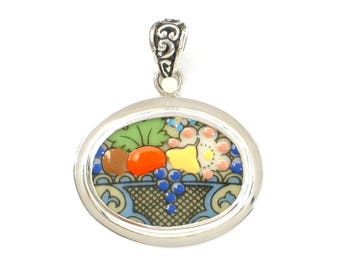 May include: A silver oval pendant with a colorful mosaic design featuring fruit and flowers. The pendant is set in a silver frame with a decorative bail.
